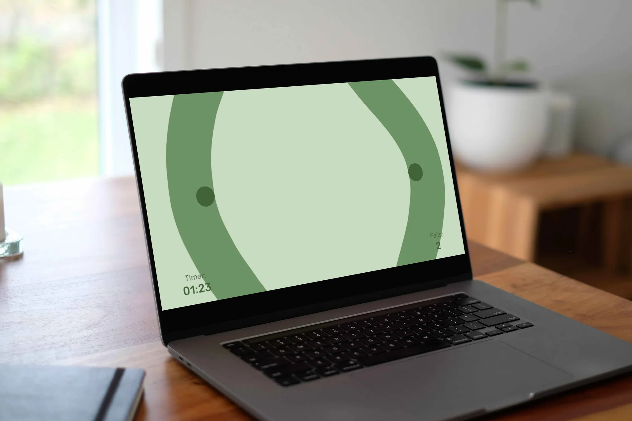 Laptop on a wooden desk showing the green circular steady-hand mini-game