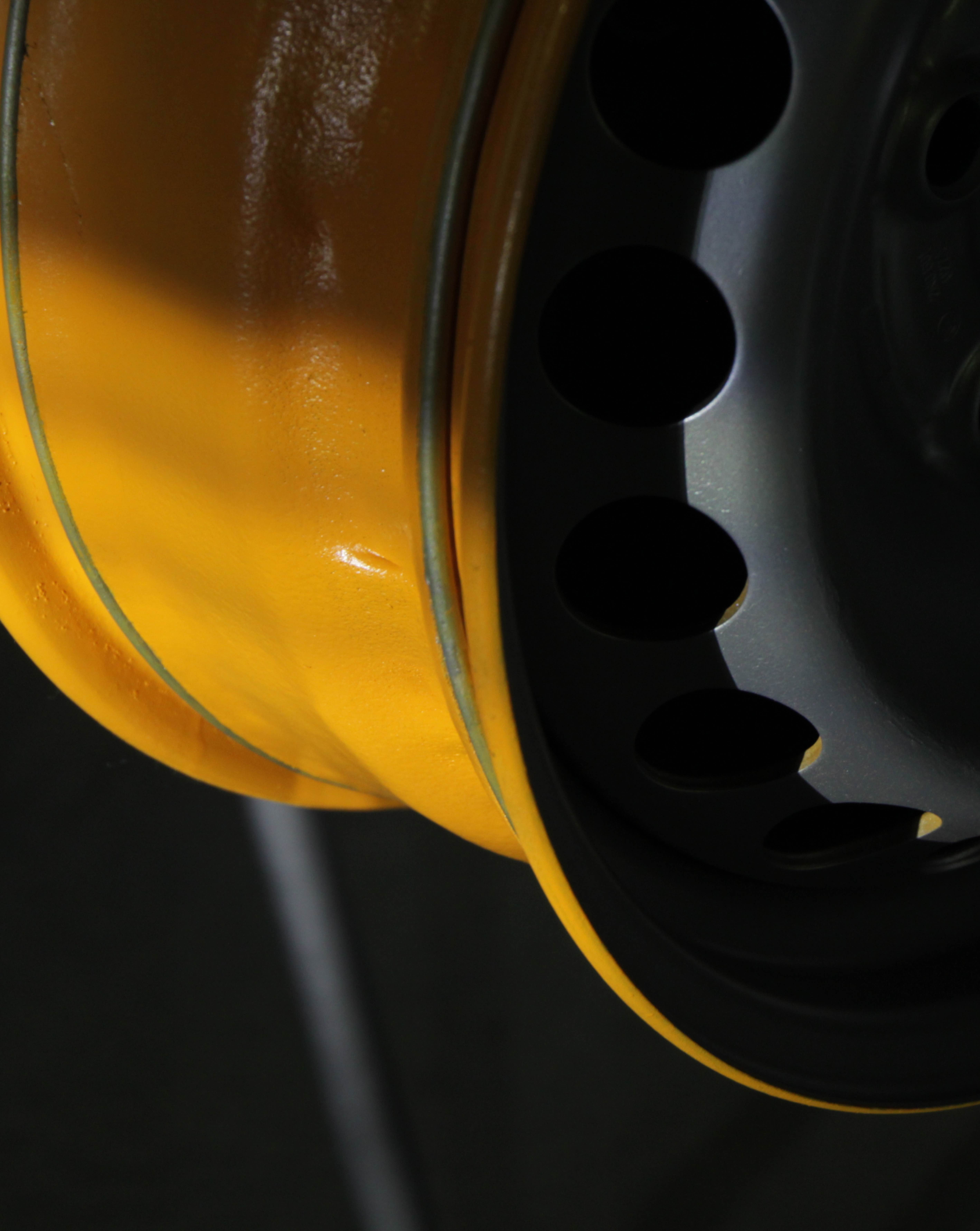 Close-up of a yellow car wheel rim against a dark background
