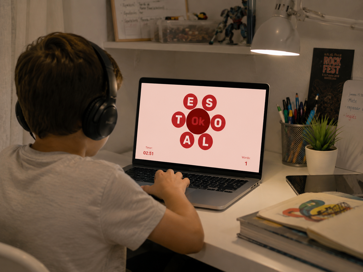 Boy with headphones playing Intellia word-formation mini-game on laptop, red letter circles on pink background