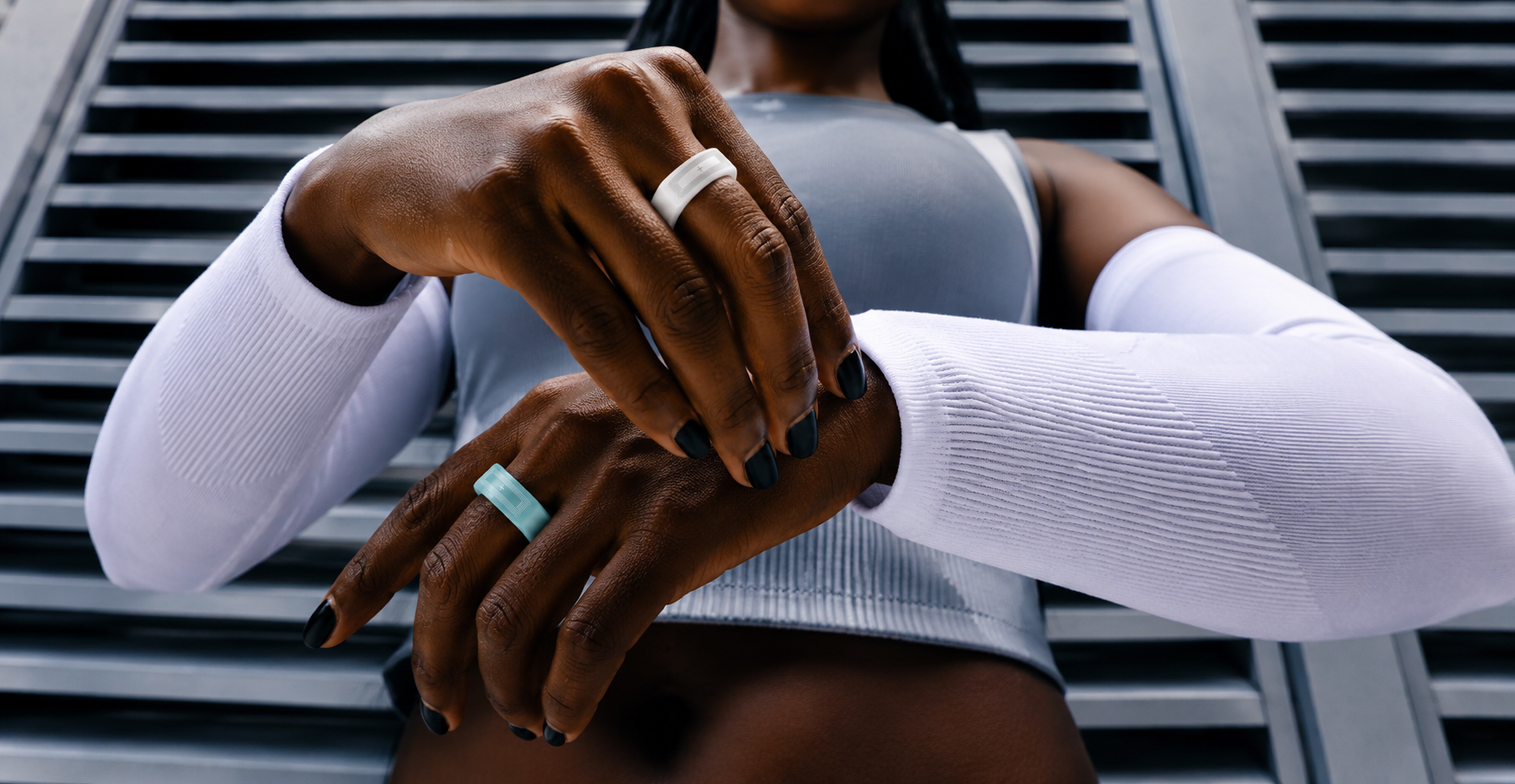 Athlete with white and mint ONNN rings against a metal louvre backdrop